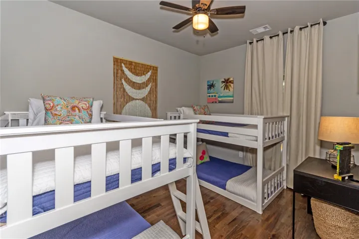 This cozy bedroom features multiple bunk beds and hardwood flooring, creating a comfortable and inviting space.