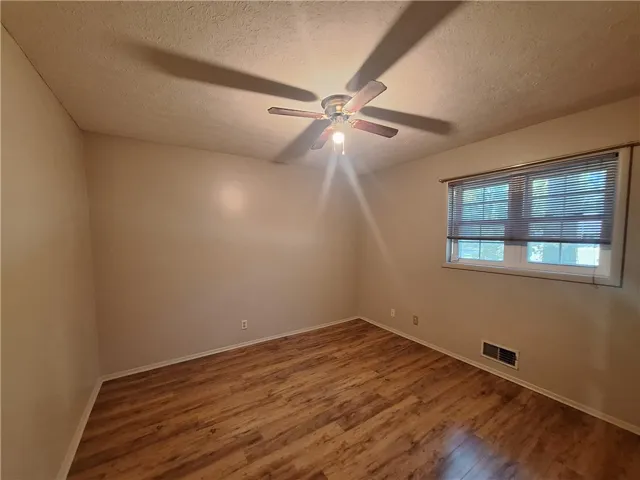 This spacious bedroom offers ample natural light and durable wood flooring.