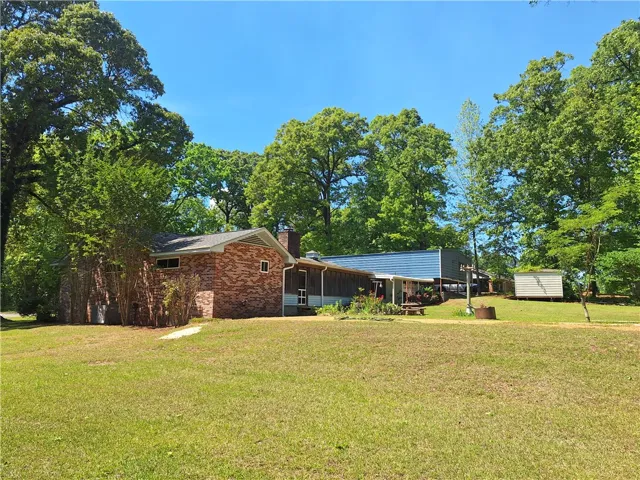 This tranquil property features a classic brick home nestled amidst lush, mature trees.