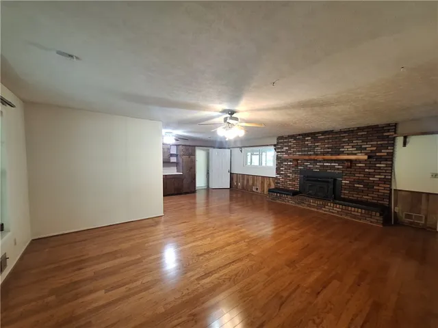 This expansive space features warm hardwood floors and a striking brick fireplace, creating a cozy atmosphere.
