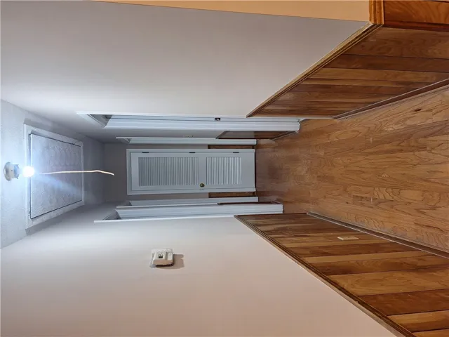 This interior hallway features warm wood flooring and a closet, creating a functional living space.