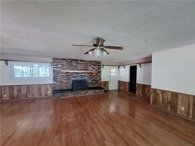 This expansive living area features lustrous wood floors and a charming brick fireplace.