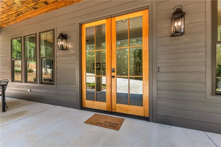 Warm wood double doors invite entry to this stylish home, complete with durable siding and outdoor lighting.