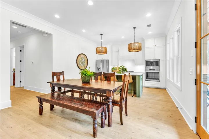 An inviting open-concept layout seamlessly merges the dining area with a modern kitchen, featuring light wood flooring and recessed lighting.