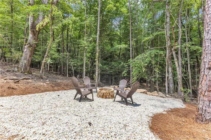 A tranquil outdoor fire pit area is nestled amongst verdant trees, perfect for gatherings.