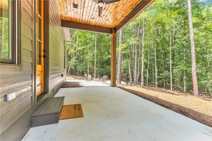An inviting covered patio offers a tranquil retreat surrounded by a verdant forest.