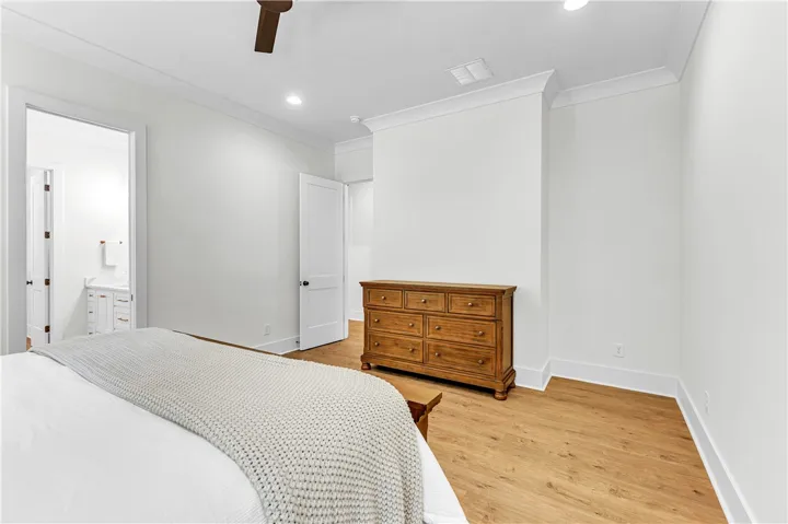 A tranquil primary bedroom with warm wood flooring opens to a private bath.