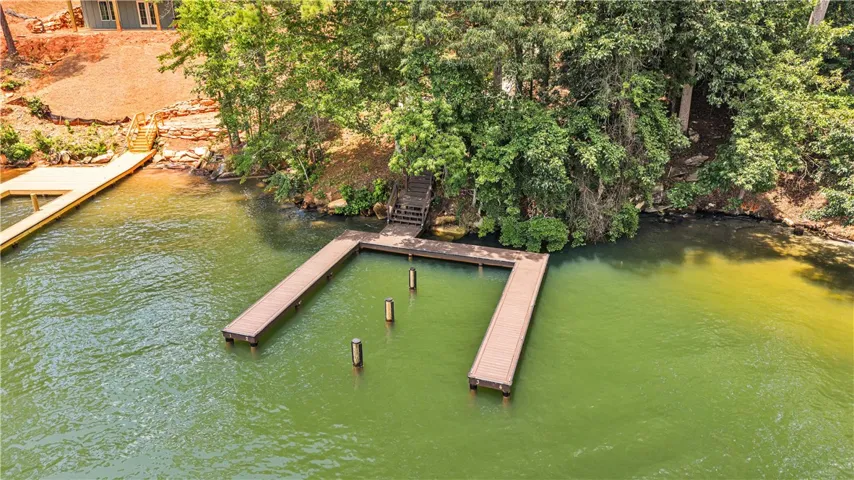 A private boat dock extends into tranquil green waters, ready for lake adventures.