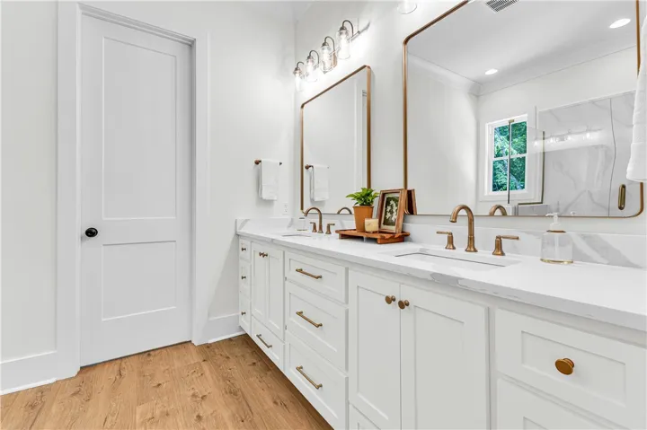 Elegant primary bath featuring a dual vanity with ample storage and sleek bronze fixtures.