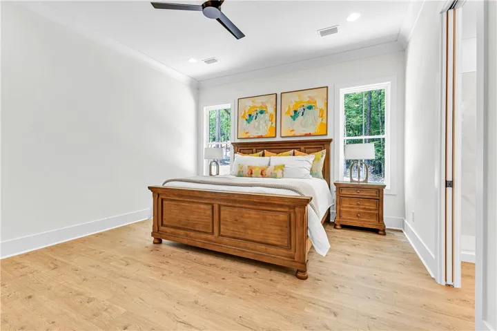 Well-lit sleeping quarters with a ceiling fan, crown molding, and light wood flooring.