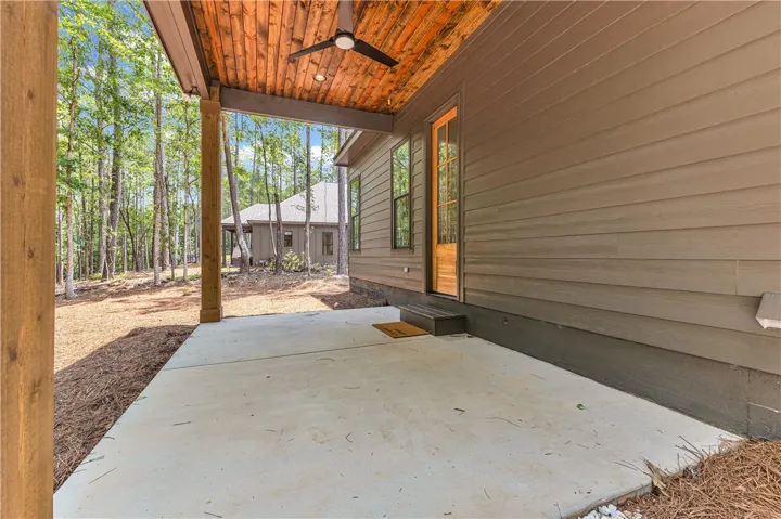 Wooded views from a shaded covered patio with a wooden plank ceiling and outdoor lighting.