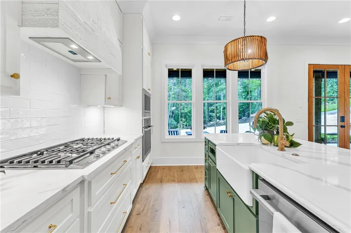 White subway tile backsplash and modern fixtures outfit this inviting kitchen with verdant outdoor views.