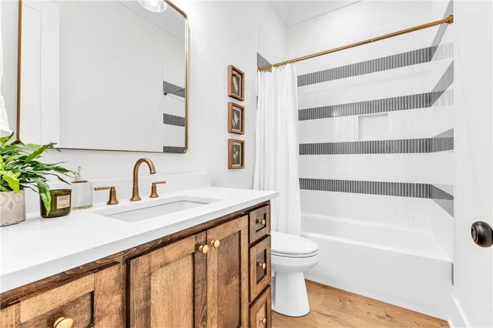 A well-lit bathroom features a rich wood vanity, contemporary hardware, and a neatly tiled shower.