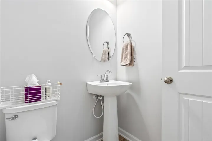 A well-appointed powder room features a pedestal sink, round mirror, and classic paneled door.