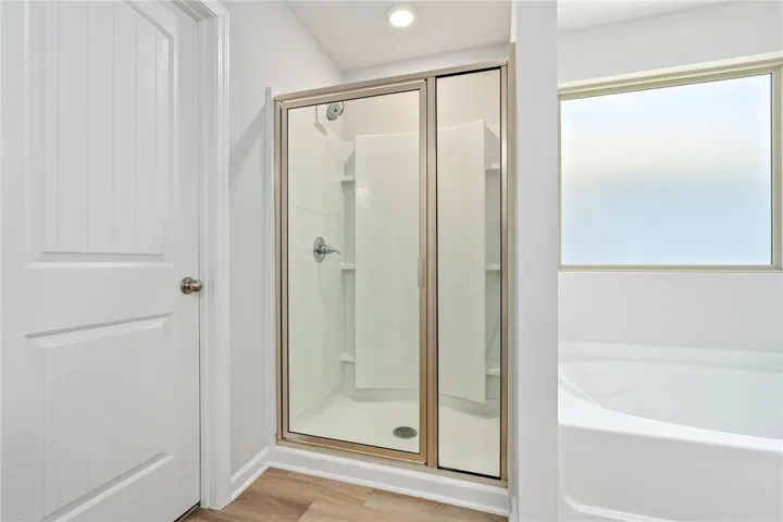 A well-appointed bath features a sleek glass-enclosed shower and a separate deep soaking tub for ultimate relaxation.