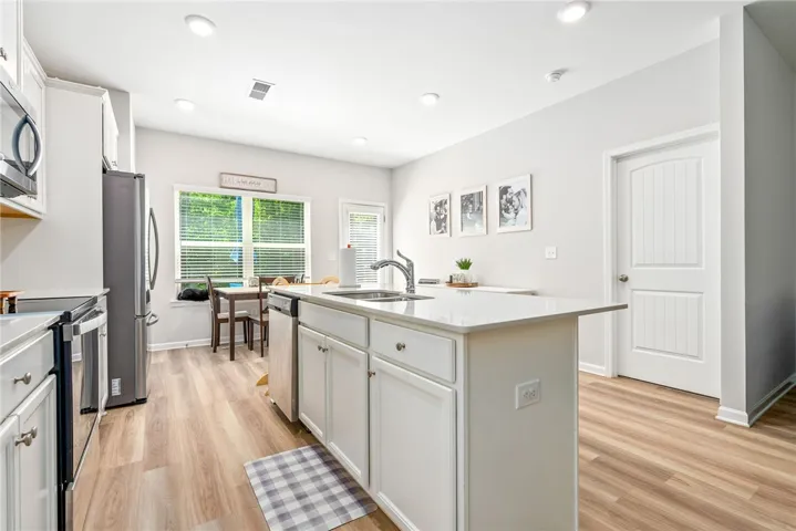 A contemporary kitchen boasts a spacious island with a sink and ample counter space, alongside modern appliances.