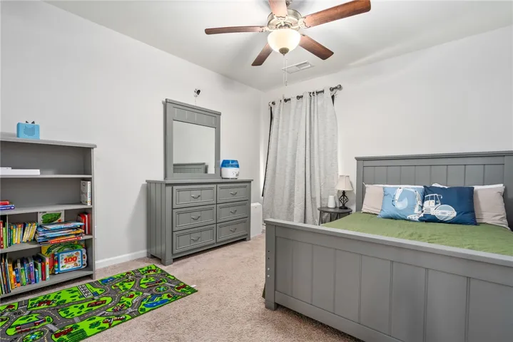 A well-lit bedroom provides ample space and neutral decor.
