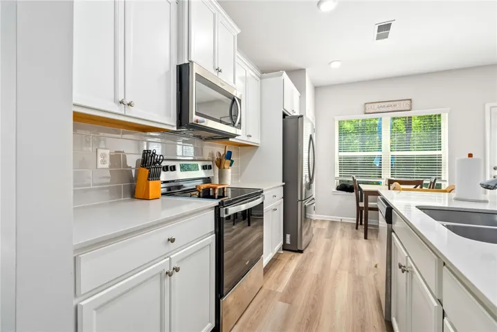 Modern kitchen featuring quartz countertops, tile backsplash, stainless appliances, and a large island.