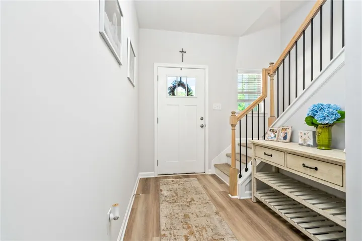 A welcoming entry features hardwood flooring and a stylish staircase leading to the upper level.