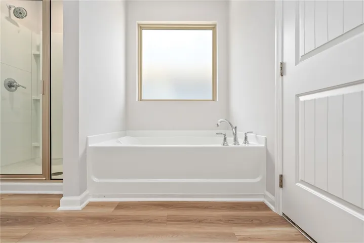 A well-lit bathroom features a deep soaking tub and a separate glass-enclosed shower.