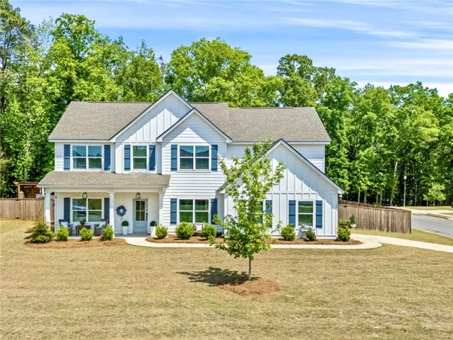 This classic white residence features a welcoming porch, lush greenery, and a well-maintained lawn.