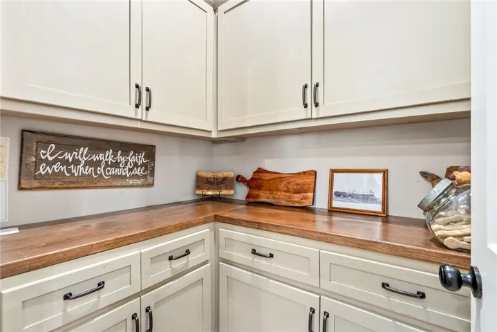 This spacious pantry features ample storage with pristine cabinetry and rich wooden countertops.