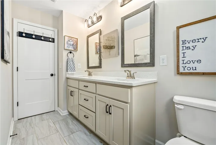 This bright bathroom features a spacious double vanity and stylish tile flooring.