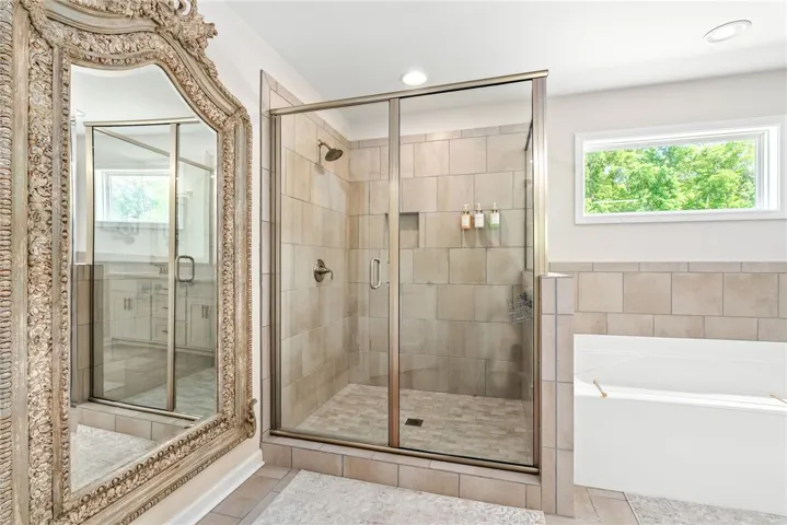 This primary bathroom features a spacious shower and a large soaking tub, creating a serene retreat.