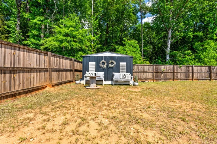 This spacious yard offers privacy and a versatile shed, perfect for storage or creative projects.