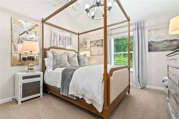 This serene bedroom offers a vaulted ceiling and a bright window overlooking lush greenery.
