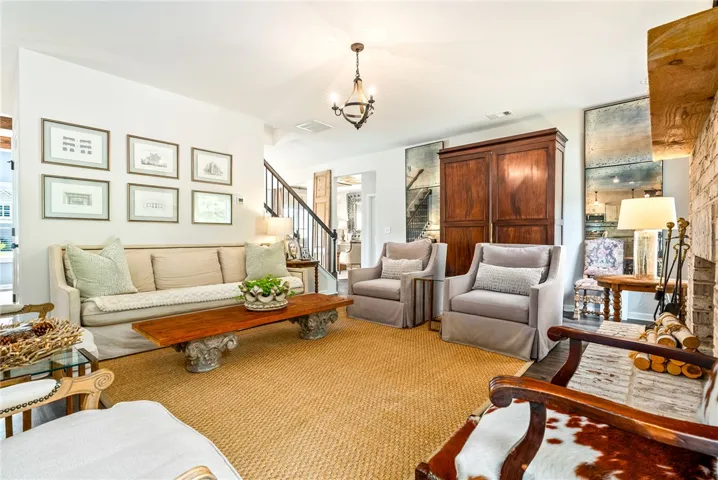 This inviting space features a charming fireplace and a grand staircase.