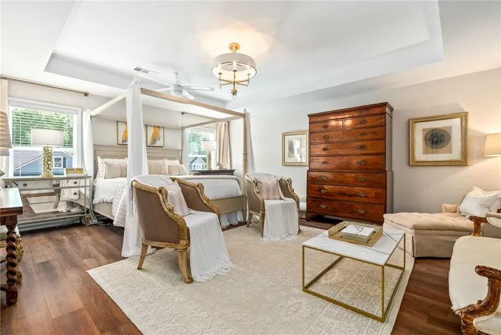 This tranquil bedroom features rich hardwood flooring and an elegant tray ceiling, perfect for relaxation.