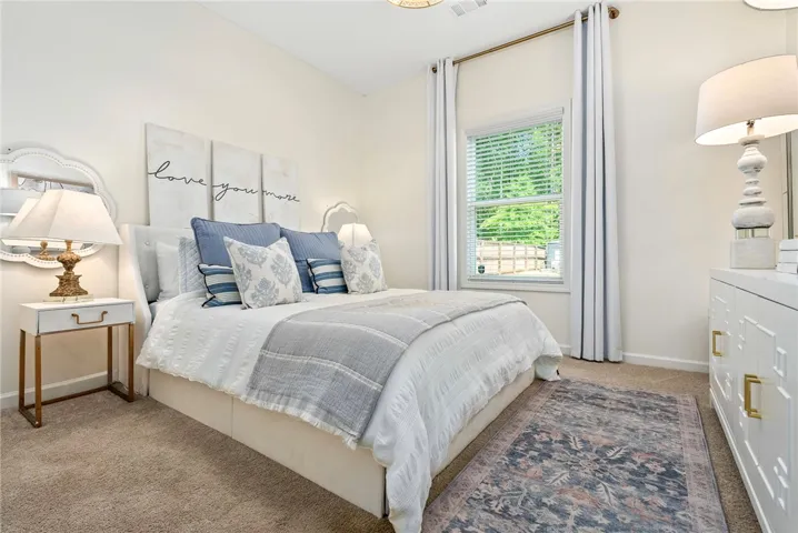 This tranquil bedroom features plush carpeting and abundant natural light, offering a comfortable retreat.