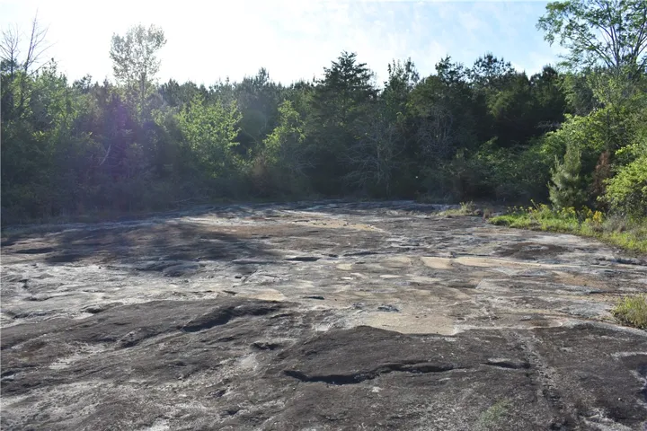 This scenic landscape features a vast expanse of natural rock formations bordered by lush trees.