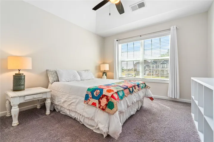 This inviting bedroom features vaulted ceilings and ample natural light, creating a bright and open atmosphere.