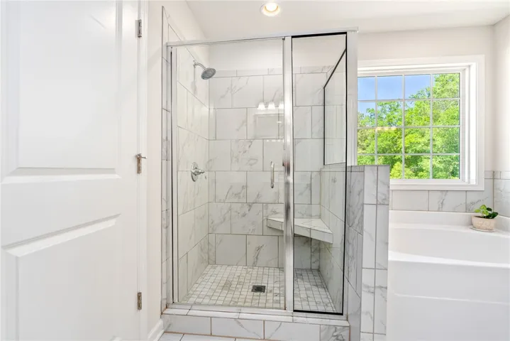 This bathroom features a sleek glass shower and a serene soaking tub with a window view.