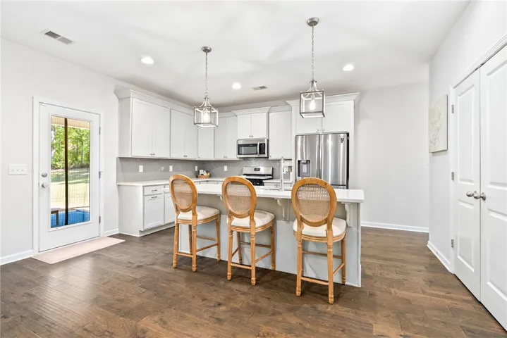 This bright kitchen features modern appliances, a kitchen island, and direct access to outdoor living.