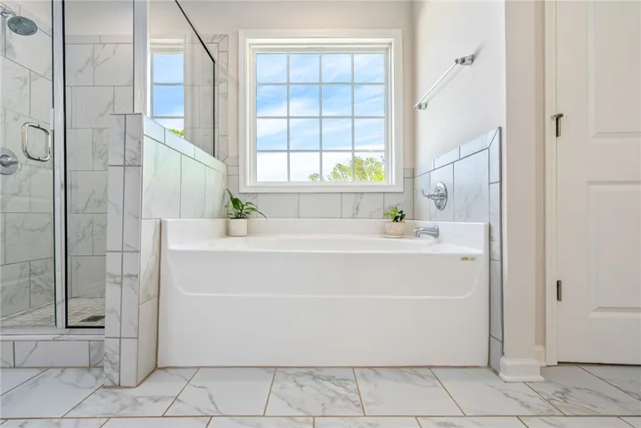 This bright bathroom features a spacious tub and shower, offering a refreshing retreat.