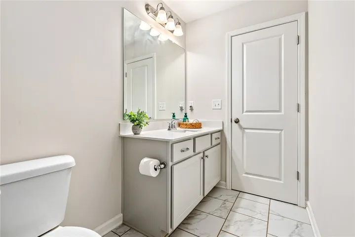 This modern bathroom features a stylish vanity and tiled flooring, offering both convenience and elegance.