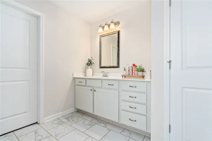 This bright bathroom features ample storage and modern tile flooring, offering practical elegance for everyday living.