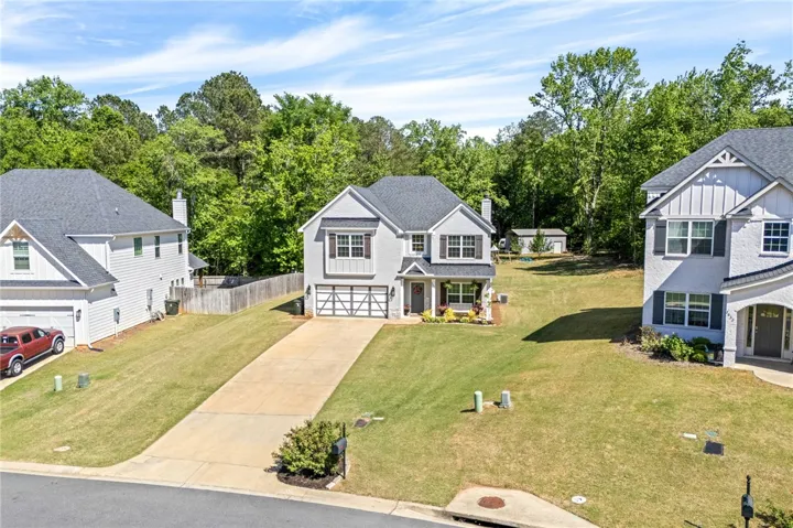 This charming residence features a classic facade, a neatly paved driveway, and lush green lawns.
