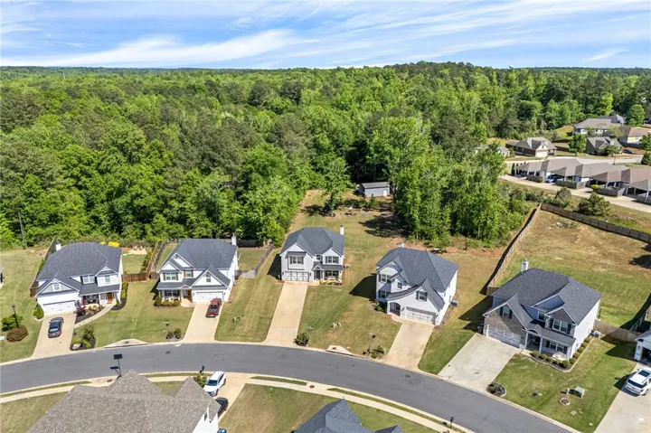An aerial perspective reveals a vibrant neighborhood nestled among lush woodlands, offering a serene living environment.