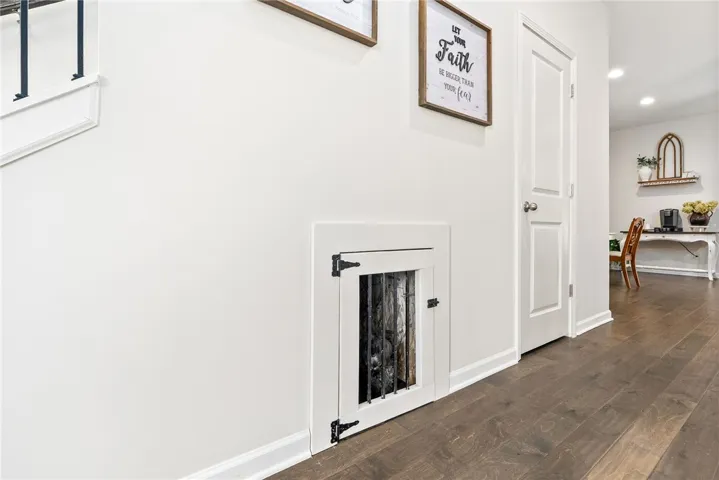 This interior hallway features a built-in pet nook and beautiful hardwood flooring.