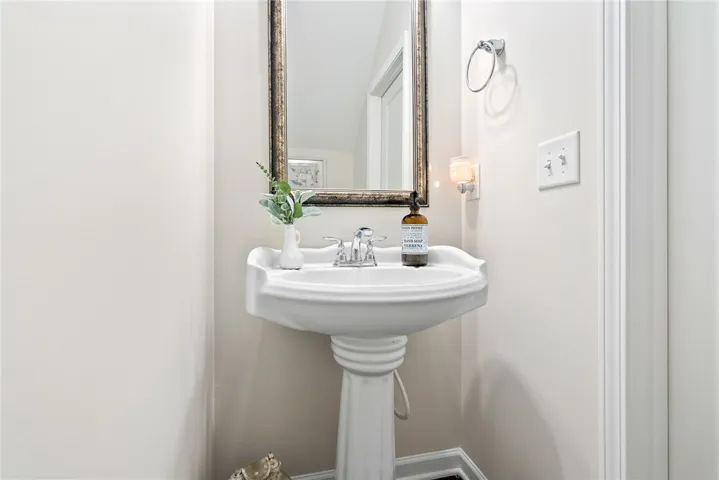 This bright bathroom features a pedestal sink and mirror, offering a refreshing and clean aesthetic.