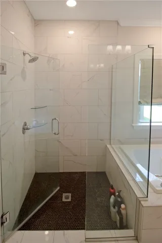 This bright bathroom features a spacious walk-in shower and a built-in tub.