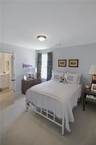 This inviting bedroom provides a comfortable retreat with soft lighting and a connected private bathroom.
