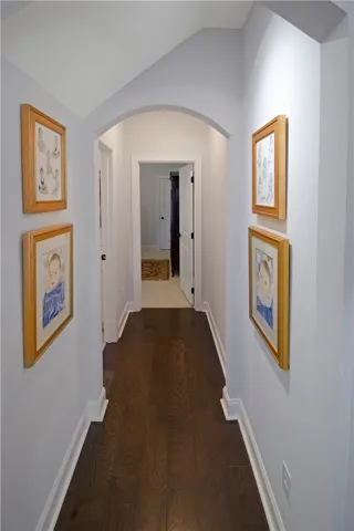 This inviting hallway features rich hardwood flooring and an elegant arched entryway.