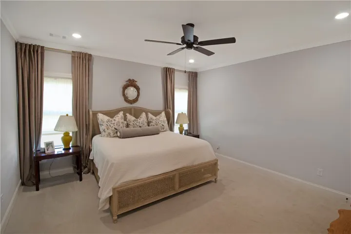 This primary bedroom offers ample space with carpet flooring and elegant crown molding.
