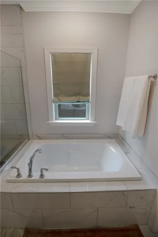 Relax in this inviting bathroom featuring a deep soaking tub and elegant tiled surround.