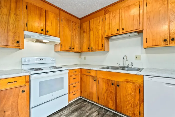 A well-lit kitchen with natural wood cabinetry and resilient flooring.